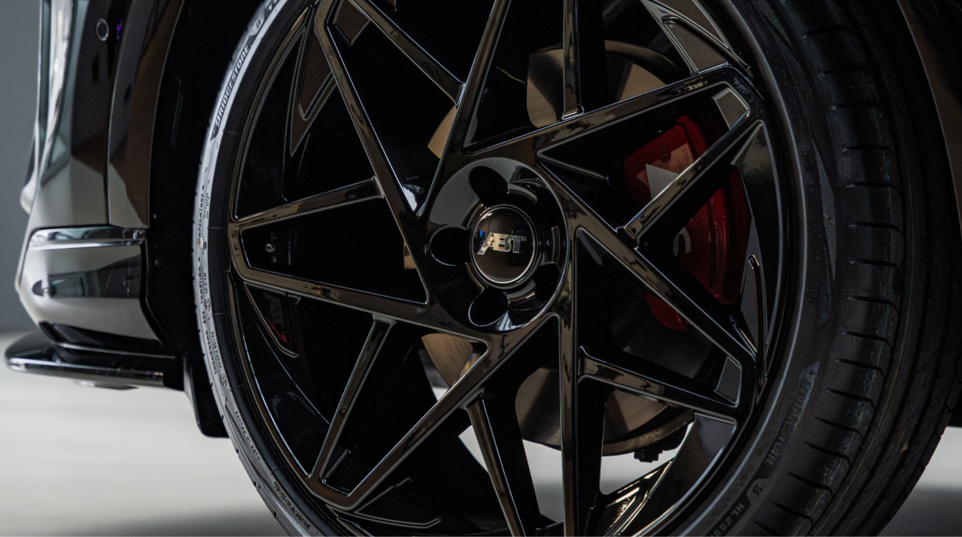 Close-up of black ABT Sportsline alloy wheel and red brake caliper